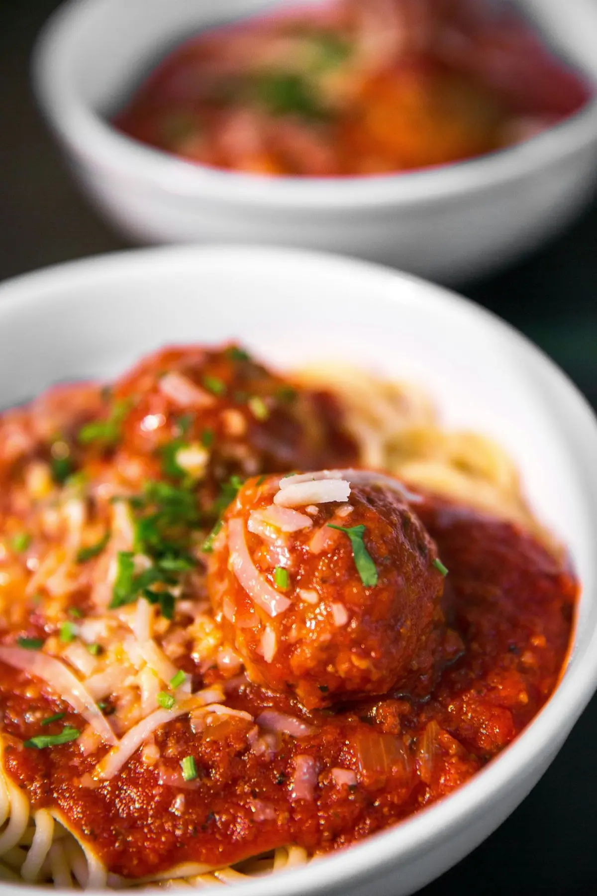 Spaghetti and meatballs with tomato sauce and parmesan in a white bowl