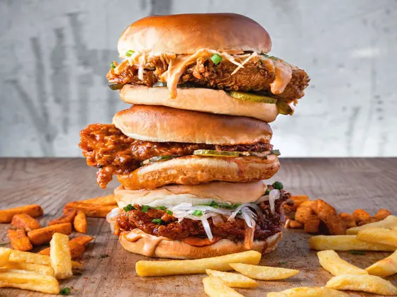 A stacked chicken sandwich with fries